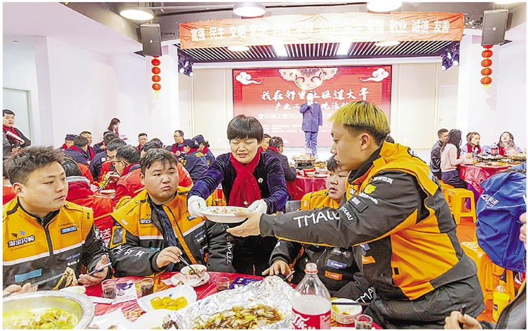 张敏华(前排中)忙着给快递小哥上菜,这样的场景,她20年来每年都在坚持。