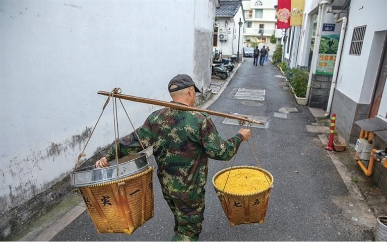 杨忠伟挑着两筐刚打完的桂花回家